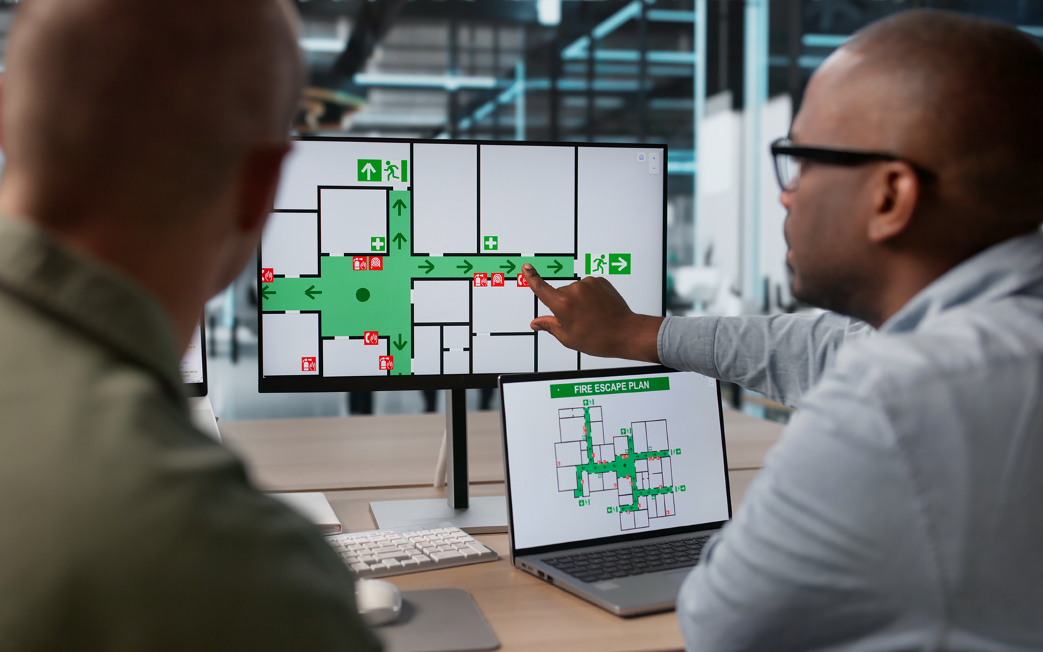 Two technicians review a fire evacuation map during emergency planning. 